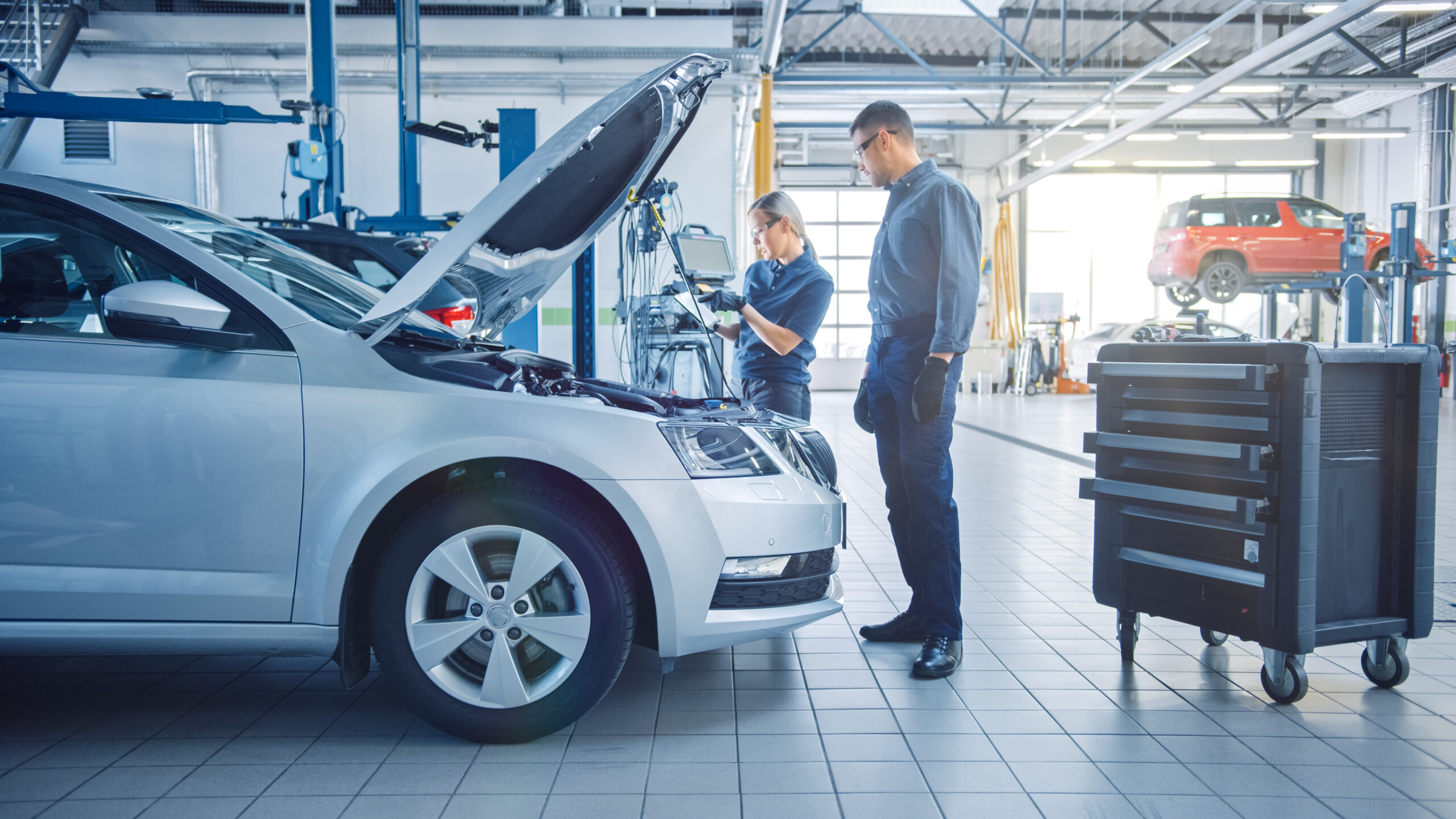 Two mechanics inspecting a car